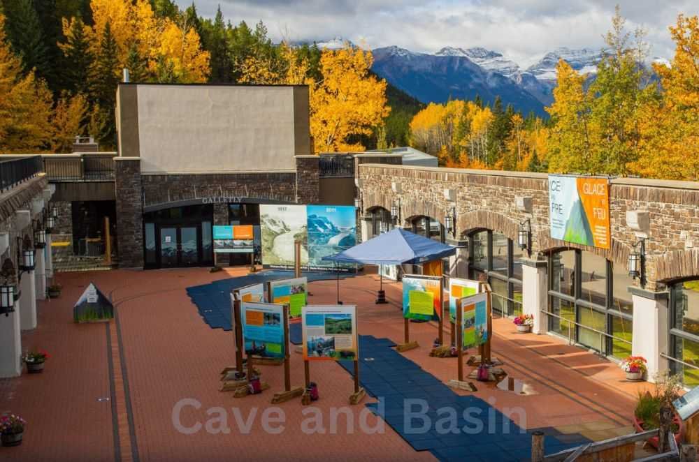 Cave and Basin National Historic Site features outdoor informational displays set against a backdrop of autumn trees and distant mountains.