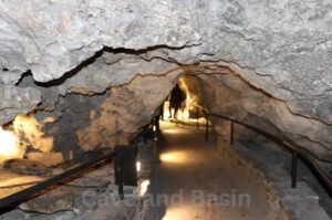 A dimly lit, narrow passage at Cave and Basin National Historic Site, with railings on both sides. Two people are visible in the distance walking through the pathway.