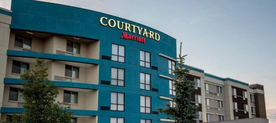 Exterior view of a Courtyard Marriott hotel building with multiple floors and large windows, surrounded by trees, ideal for those seeking hotels near West Edmonton Mall.