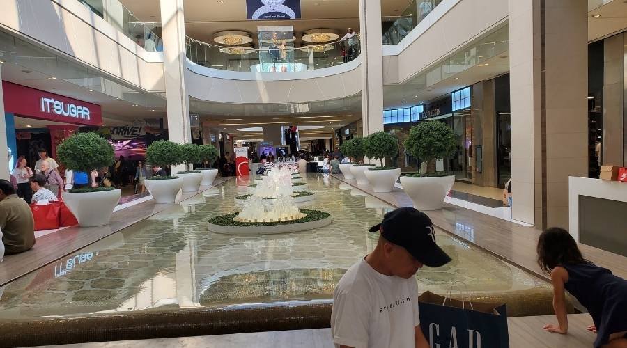 Shoppers walk past a decorative water fountain and planters in the bustling West Edmonton Mall.