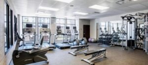 Modern gym with treadmills, stationary bikes, weight benches, free weights, and exercise machines. Wall mirrors and large windows provide natural light. Perfect for guests of hotels near West Edmonton Mall looking to stay fit during their visit.