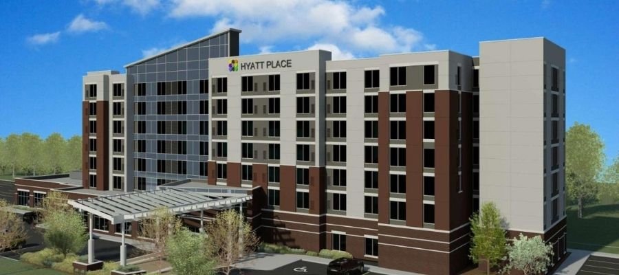 Exterior view of the Hyatt Place hotel building under a blue sky with greenery and landscaping in the foreground, conveniently situated among hotels near West Edmonton Mall.