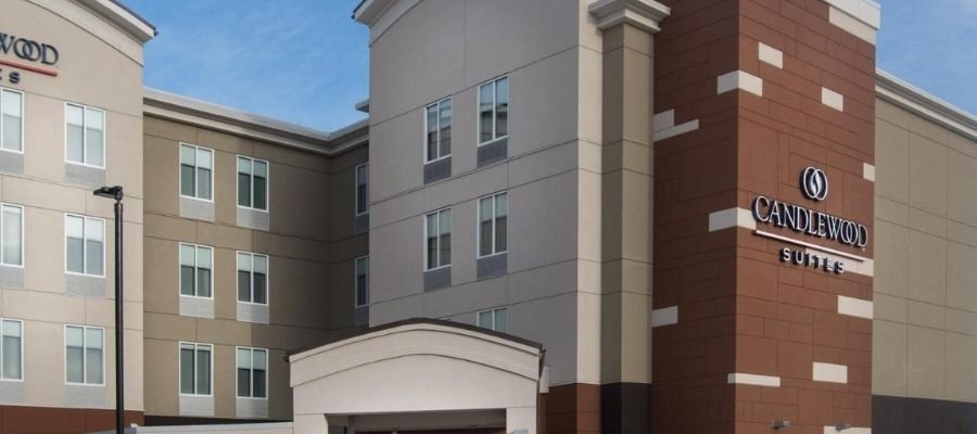 Exterior view of a Candlewood Suites hotel building with a beige and brown facade, several windows, and brand signage under a clear sky. Ideal for travelers looking for hotels near West Edmonton Mall.