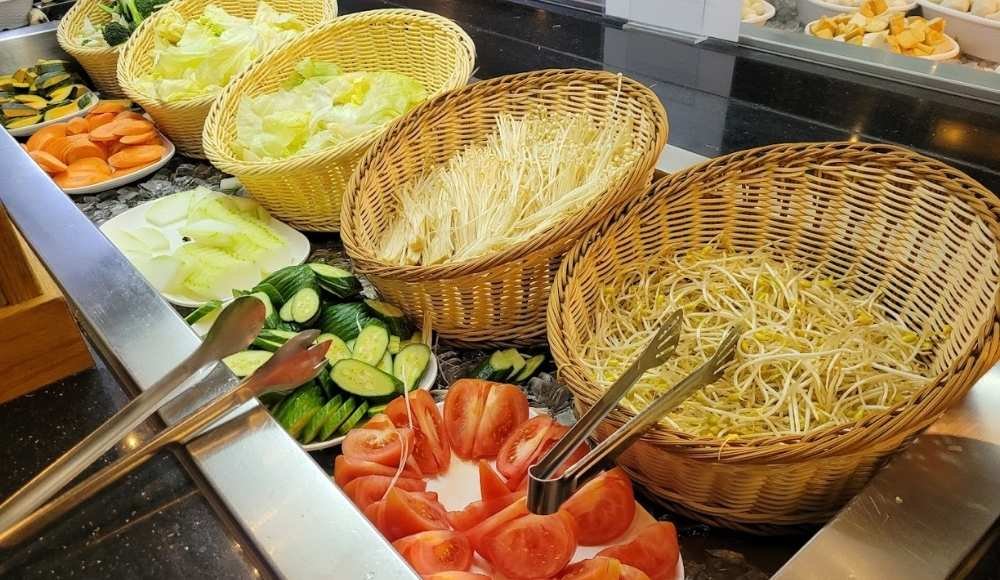 A variety of fresh vegetables, including lettuce, bean sprouts, cucumbers, and sliced tomatoes, are artfully arranged in wicker baskets at buffets in Edmonton.