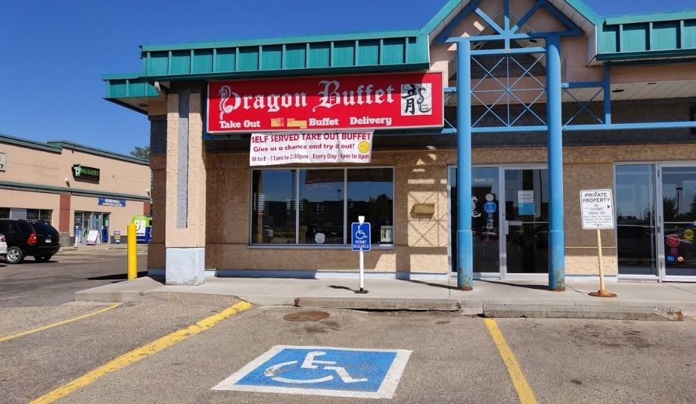 The exterior of Dragon Buffet restaurant, a popular spot among buffets in Edmonton, features a sign advertising takeout, buffet, and delivery. A handicap parking space is visible in the foreground.