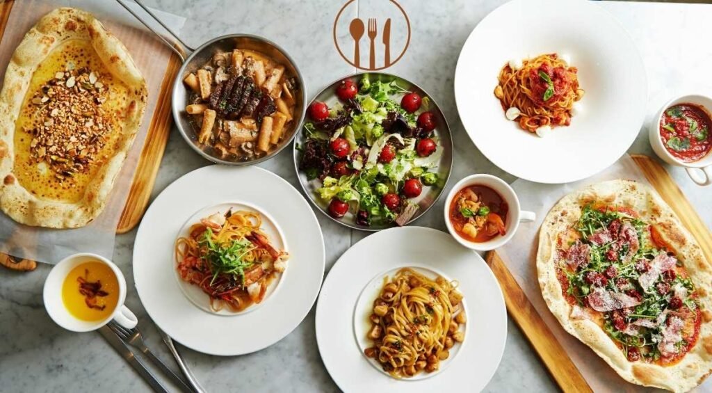 An overhead view of various dishes on a marble table, including pasta, salad, and flatbreads with various toppings, reminiscent of the diverse plates found in Edmonton's Indian restaurants.