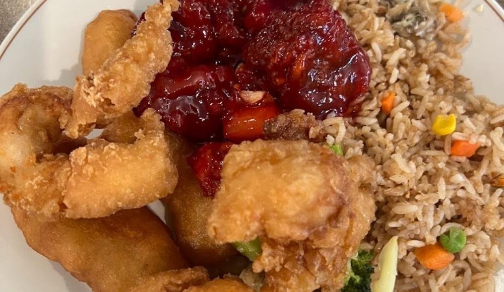 A delightful plate featuring fried chicken pieces, sweet and sour chicken, and fried rice with mixed vegetables—it's reminiscent of the diverse offerings you'll find at the best buffets in Edmonton.