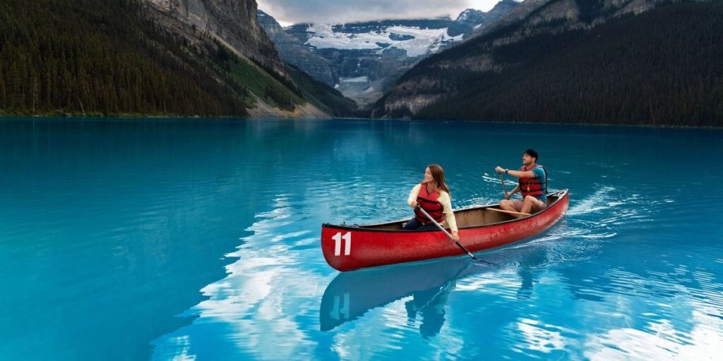 Two people paddle a red canoe on Lake Louise