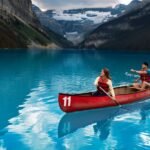 Two people paddle a red canoe on Lake Louise
