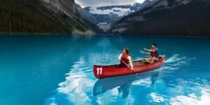 Two people paddle a red canoe on Lake Louise