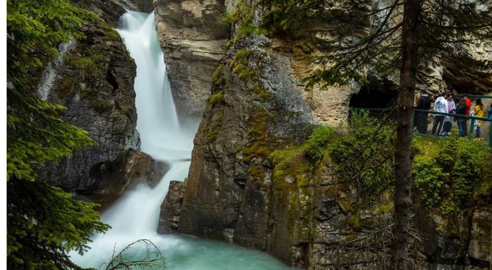 A group of people stands on a viewing platform at Johnston Canyon.