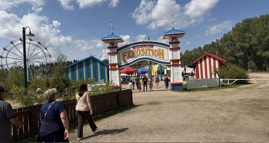 People walk toward the Fort Edmonton Park Exhibition ground with rides and games